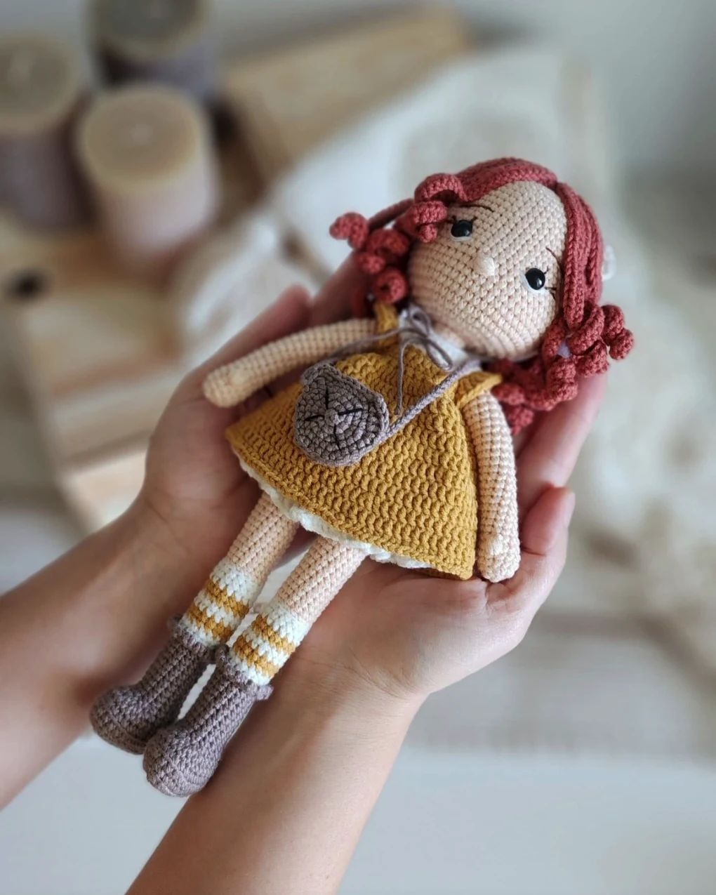 Crochet doll with red hair and a mustard dress held in two hands