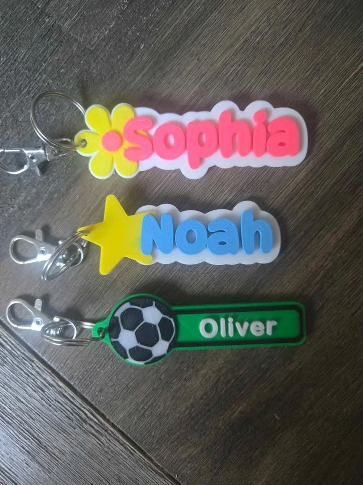 A 3D printed bag tag with a child's name beside a star design, clipped to a school bag.