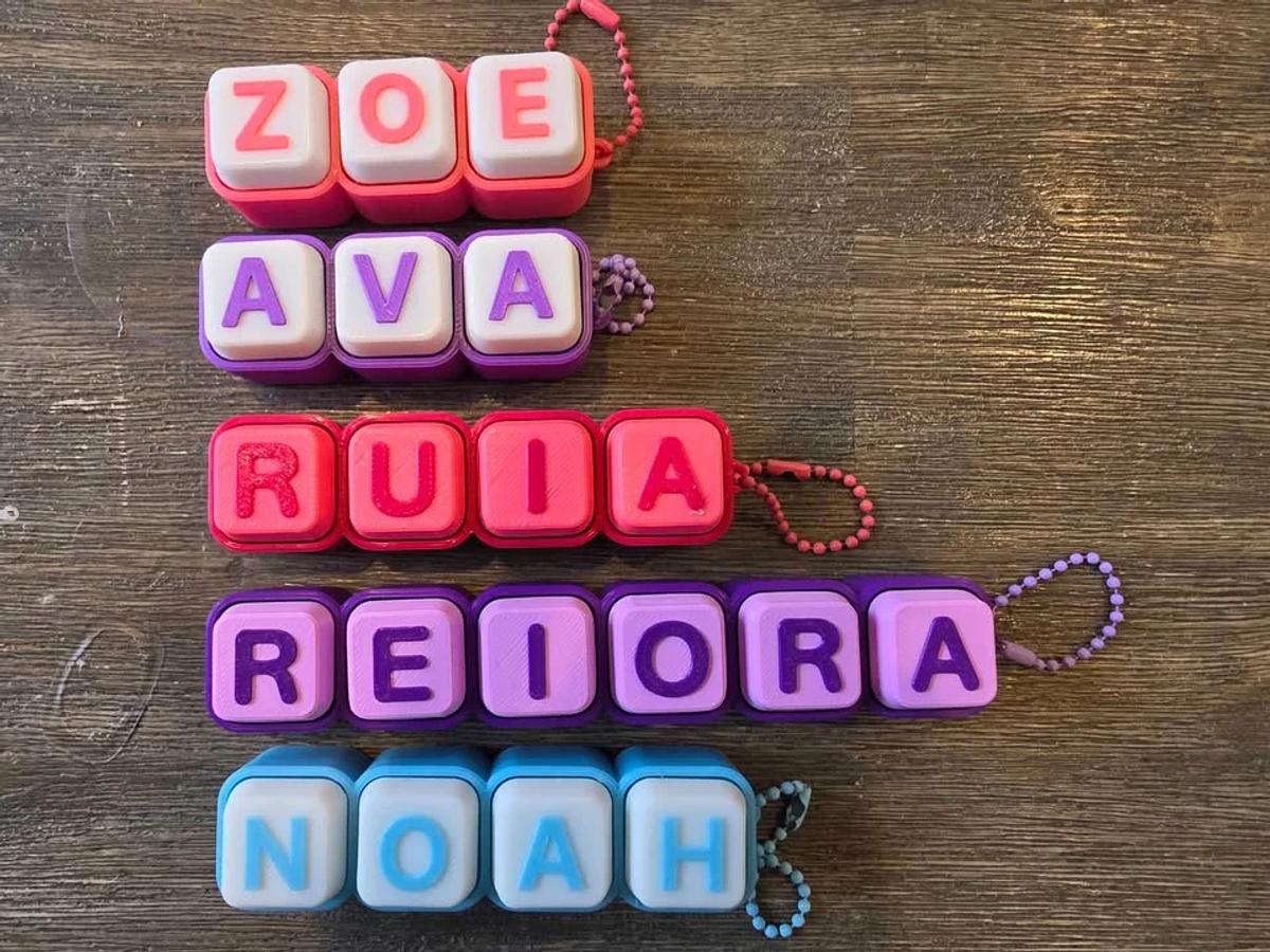 A name keychain made from clicky keyboard keys, each key printed with one letter of the name.