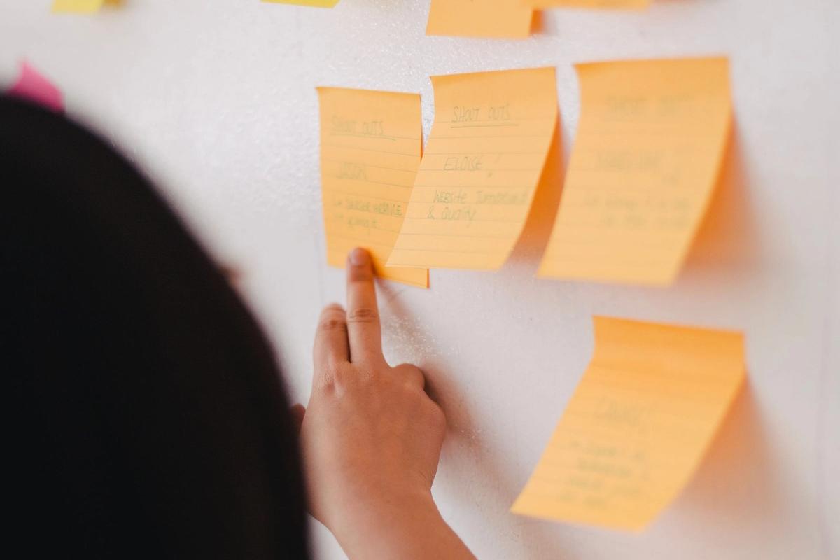 Hand placing orange sticky notes on a white wall