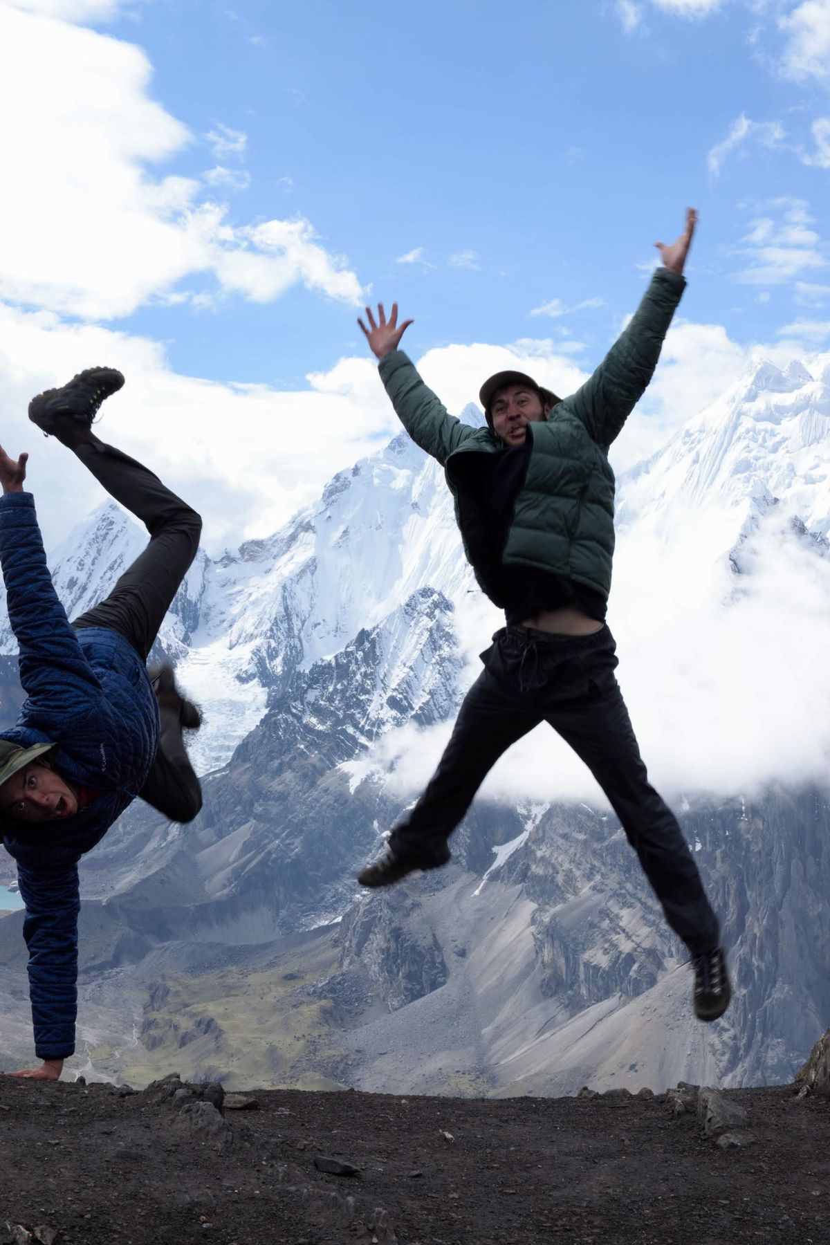 Jack and Max jumping for a photo with a mountain in the background
