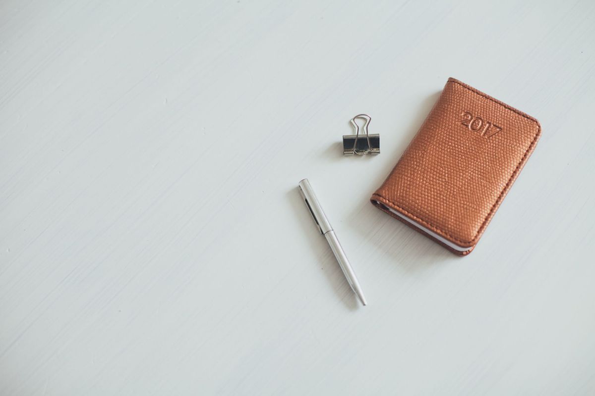 Leather notebook embossed with 2017, a pen and a binder clip on a white table