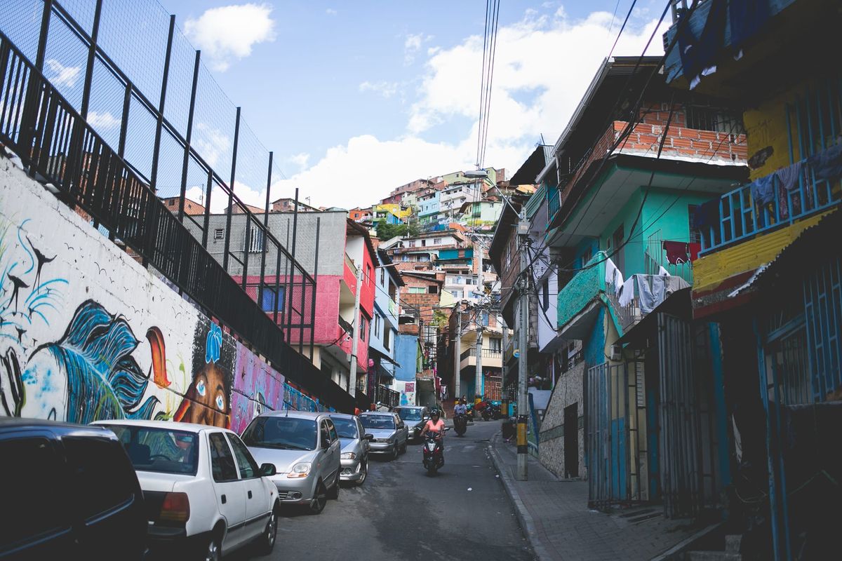 Steep street in a hillside neighborhood with colorful murals and houses