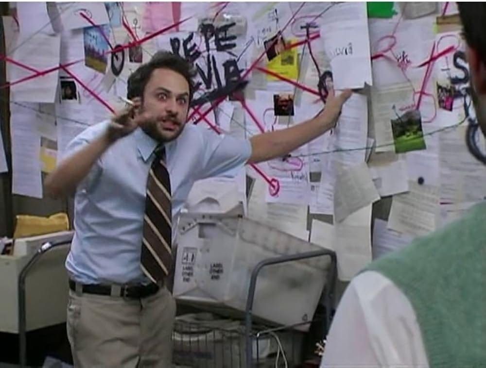The “conspiracy board” meme: a man in a tie excitedly pointing at a wall of papers connected by red string