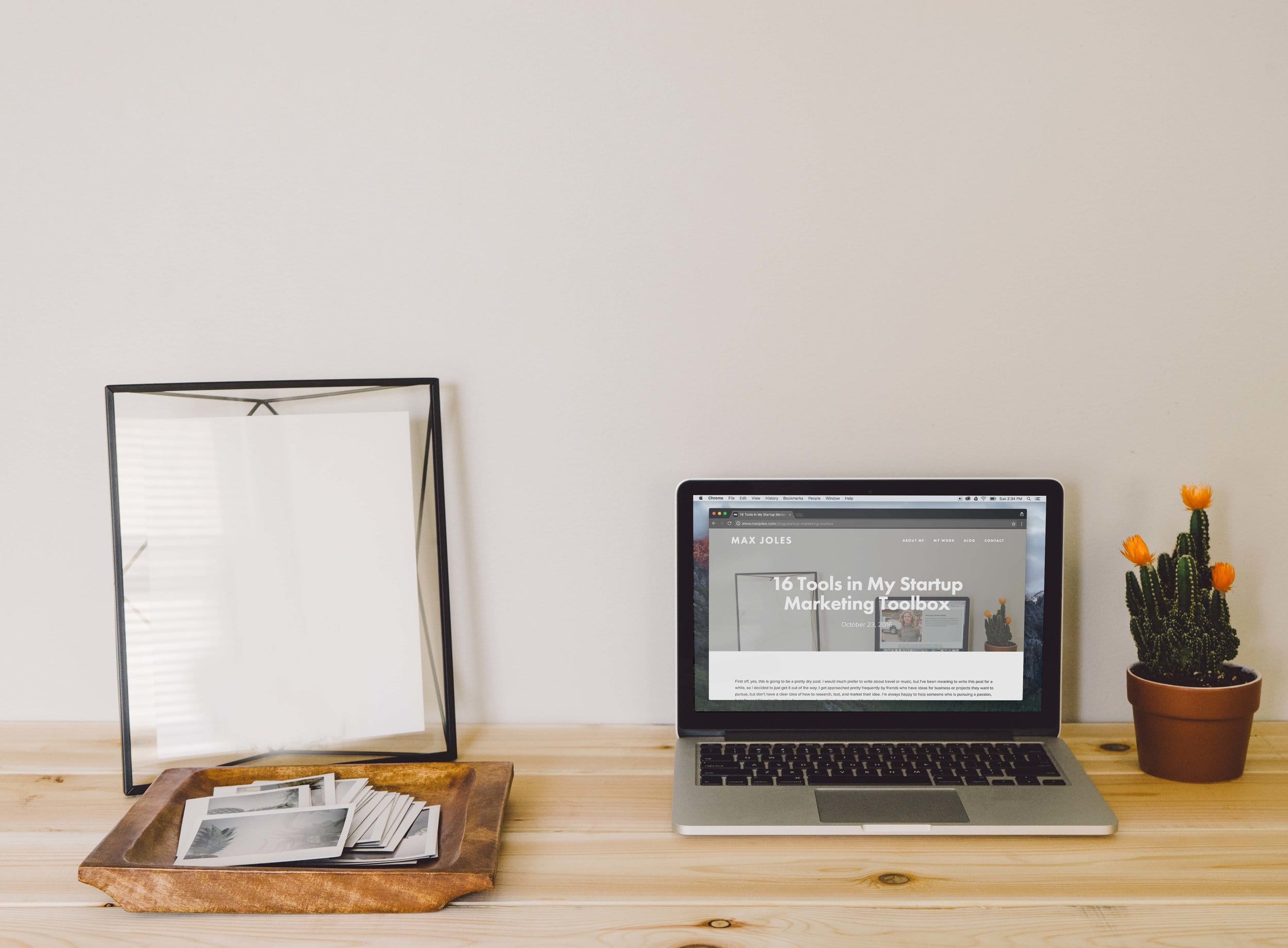Laptop, framed print and potted cactus on a wooden desk