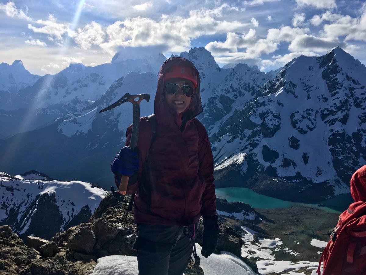 Taylor holding an ice pick and smiling atop the mountain