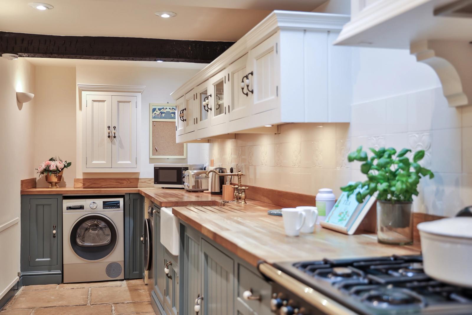 Kitchen with sage green cabinetry, stainless steel appliances, island counter, and wooden surfaces