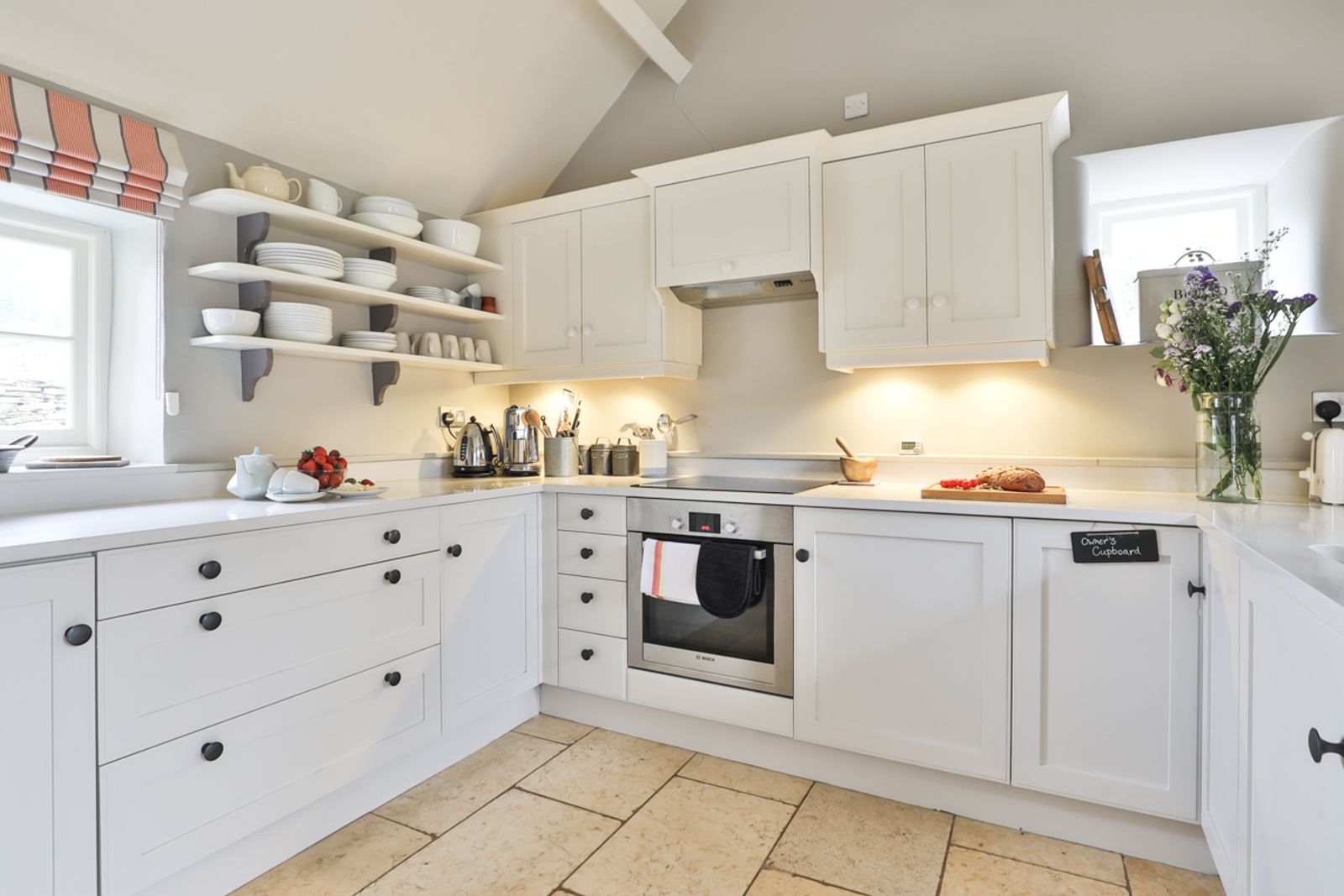 Kitchen with white cabinets, counters and natural light