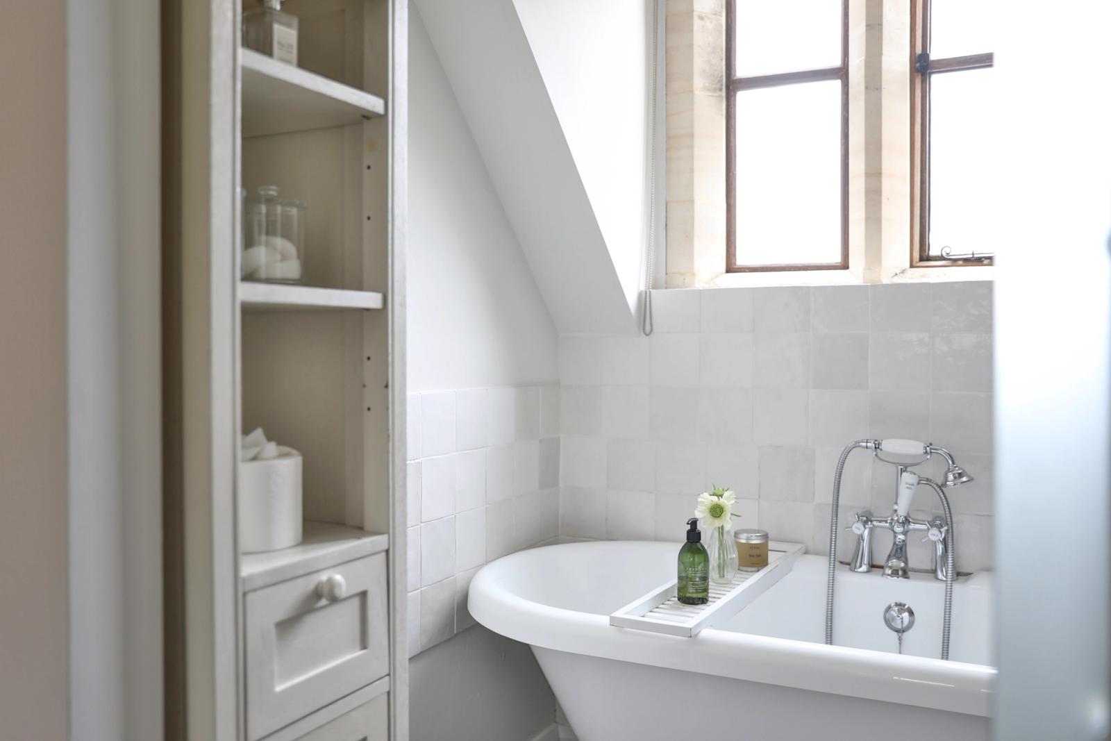 Bright bathroom with white sink, open wooden shelving, and window with natural light