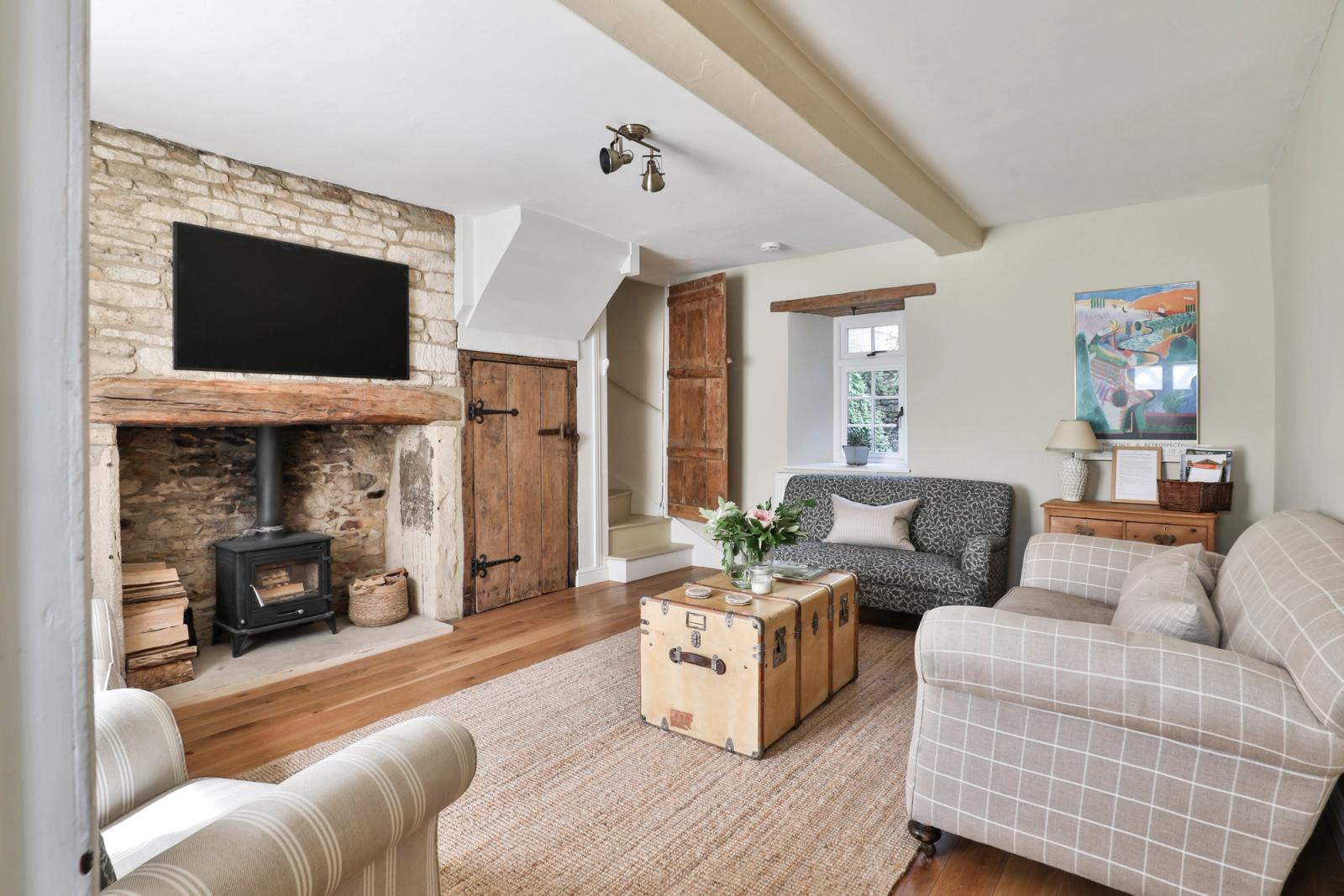 Lounge with fireplace, seating, television, wooden beams, and cream walls