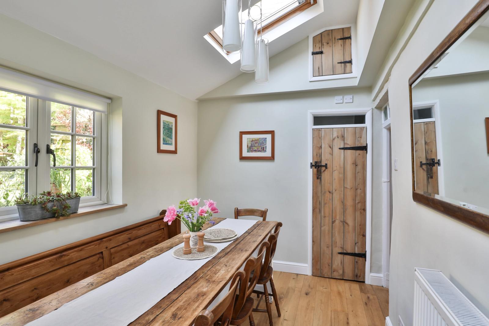 Dining room with wooden table, windows, natural lighting, and cream walls