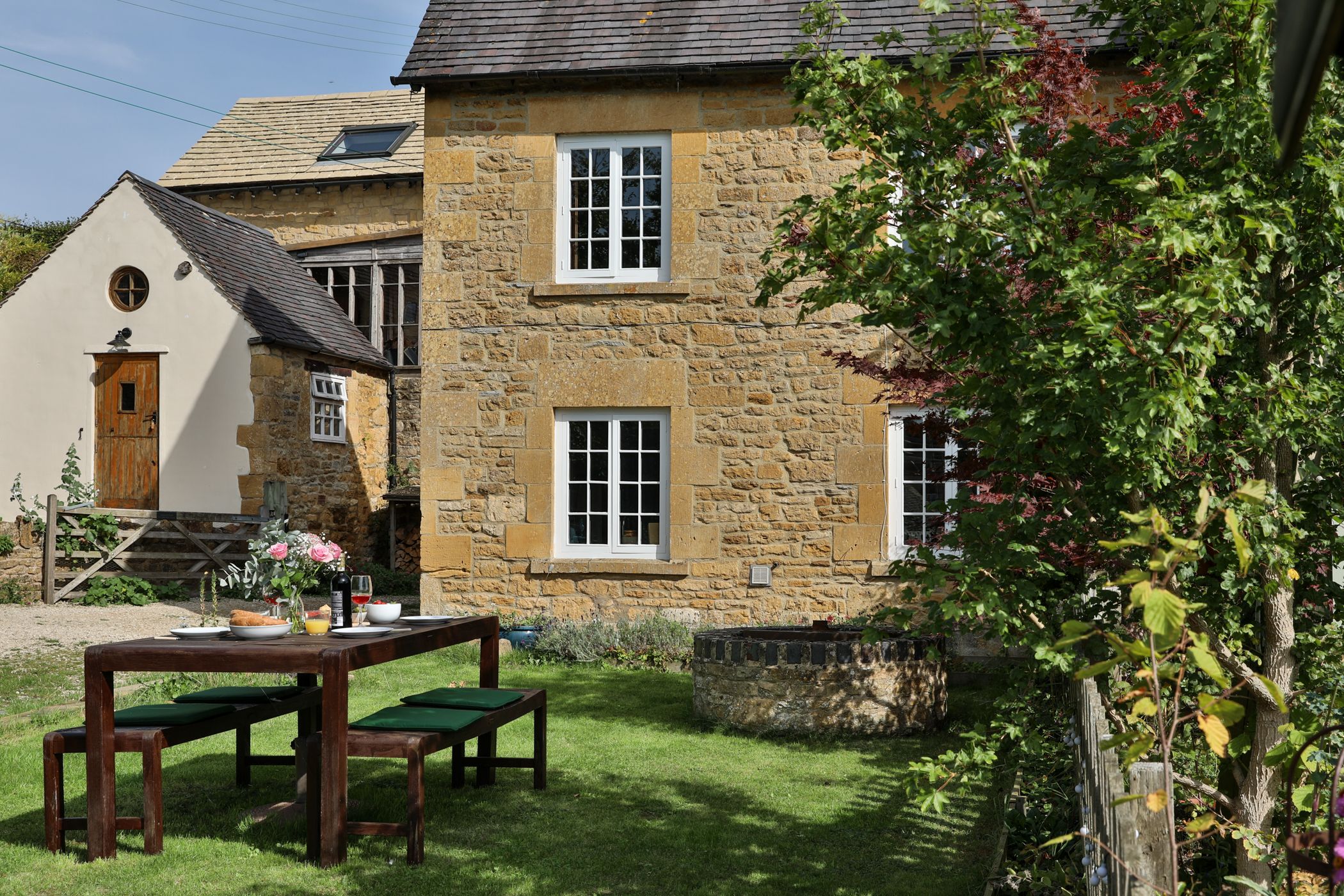 Stone cottage exterior with ivy-covered wall and green garden