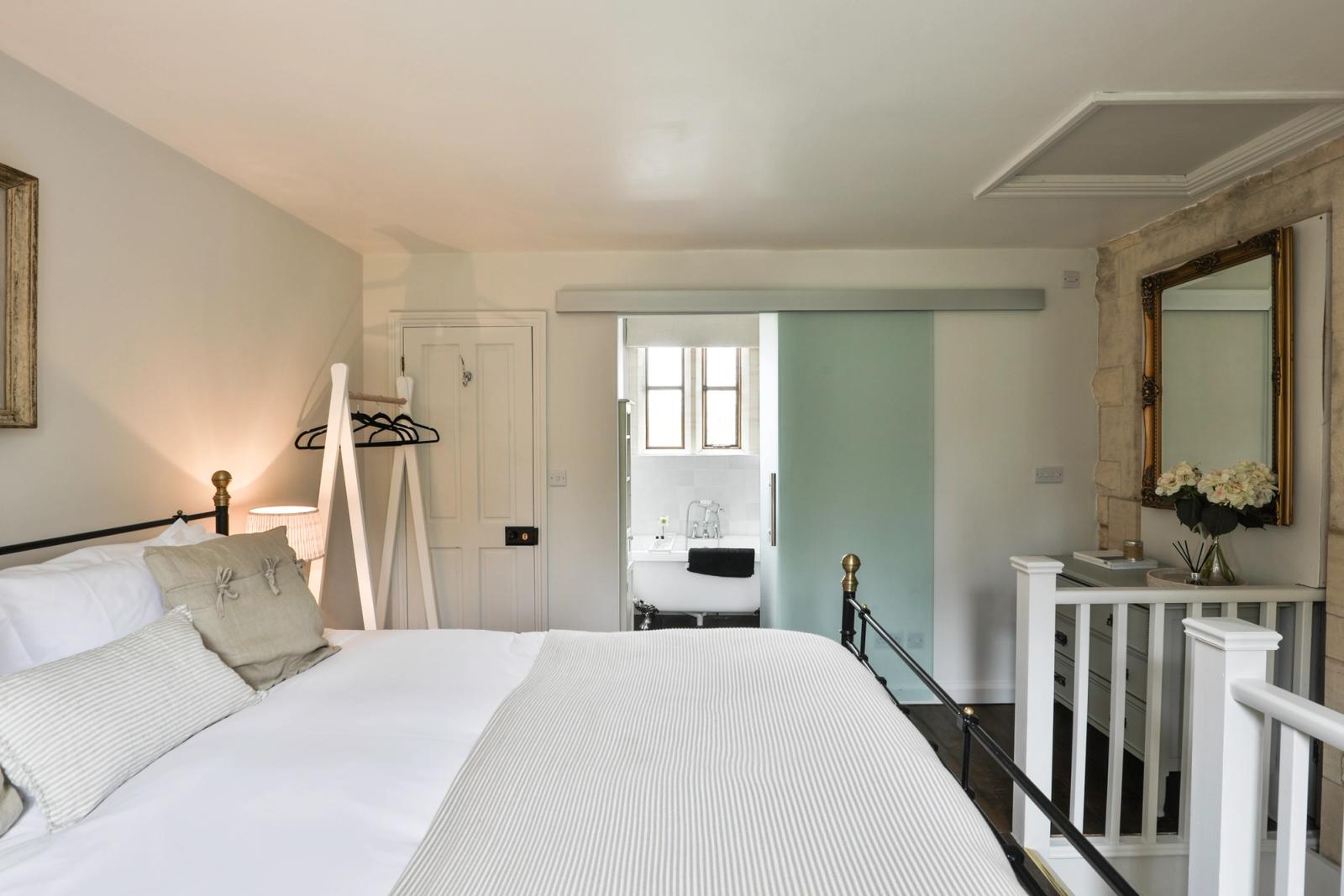 Spacious bedroom with superking white bed, pale walls, bedside lamp, and window with natural light