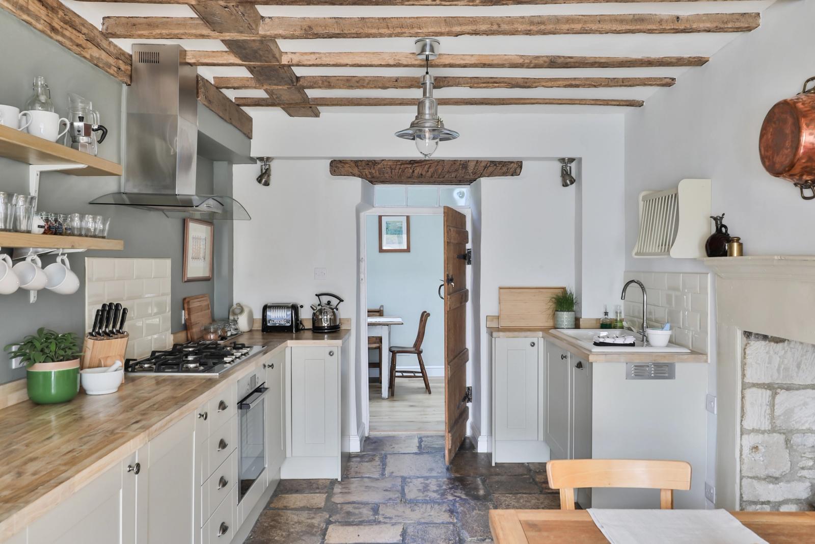 Kitchen with white cabinetry, wooden beams, countertops, and appliances