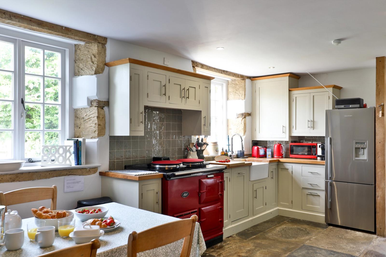 Kitchen with wooden cabinets, red Aga stove, and large windows