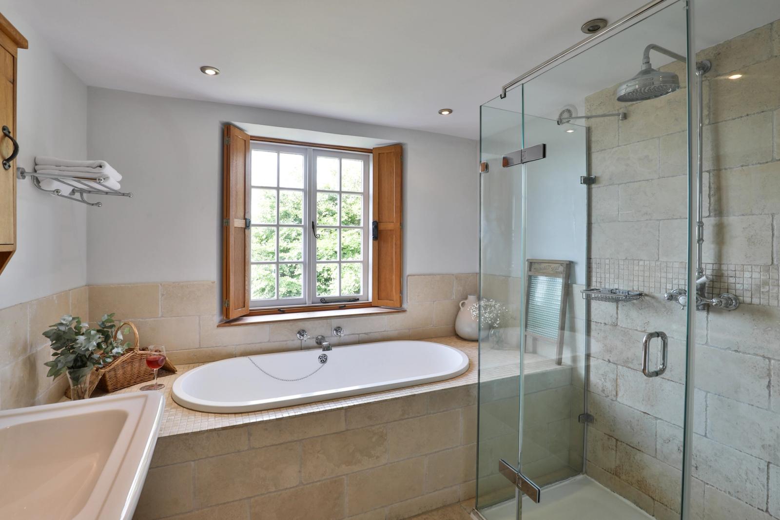 Bathroom with white bathtub, glass shower enclosure, and natural light