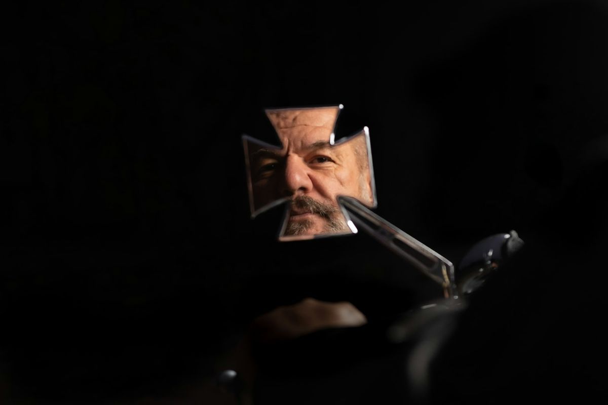 A close-up of a man carefully trimming his moustache with small pointed scissors