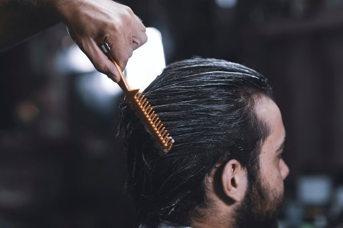 A man drawing a comb through a full beard to set its shape
