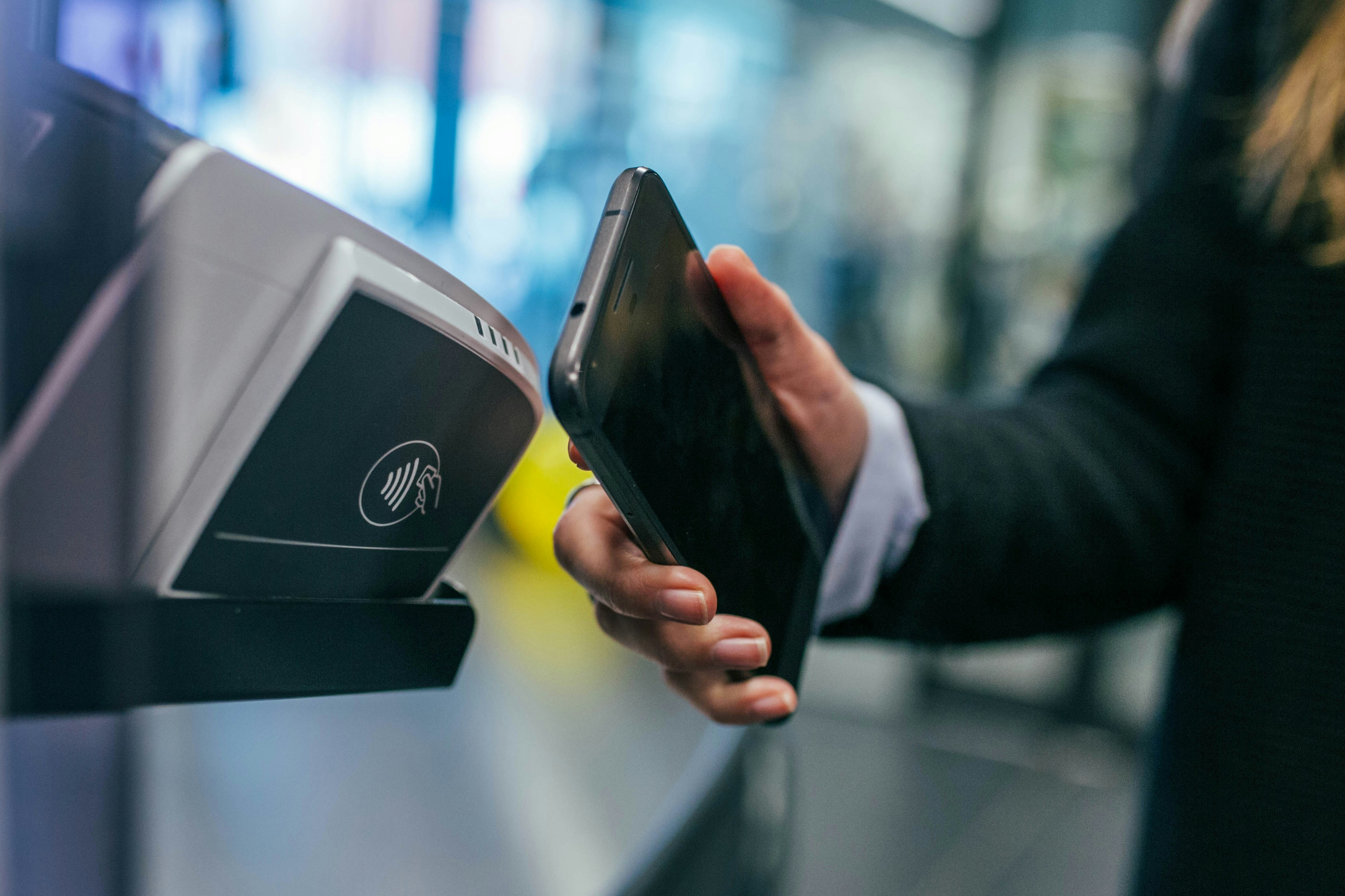 Customer using mobile phone to complete a secure NFC payment on a card reader.