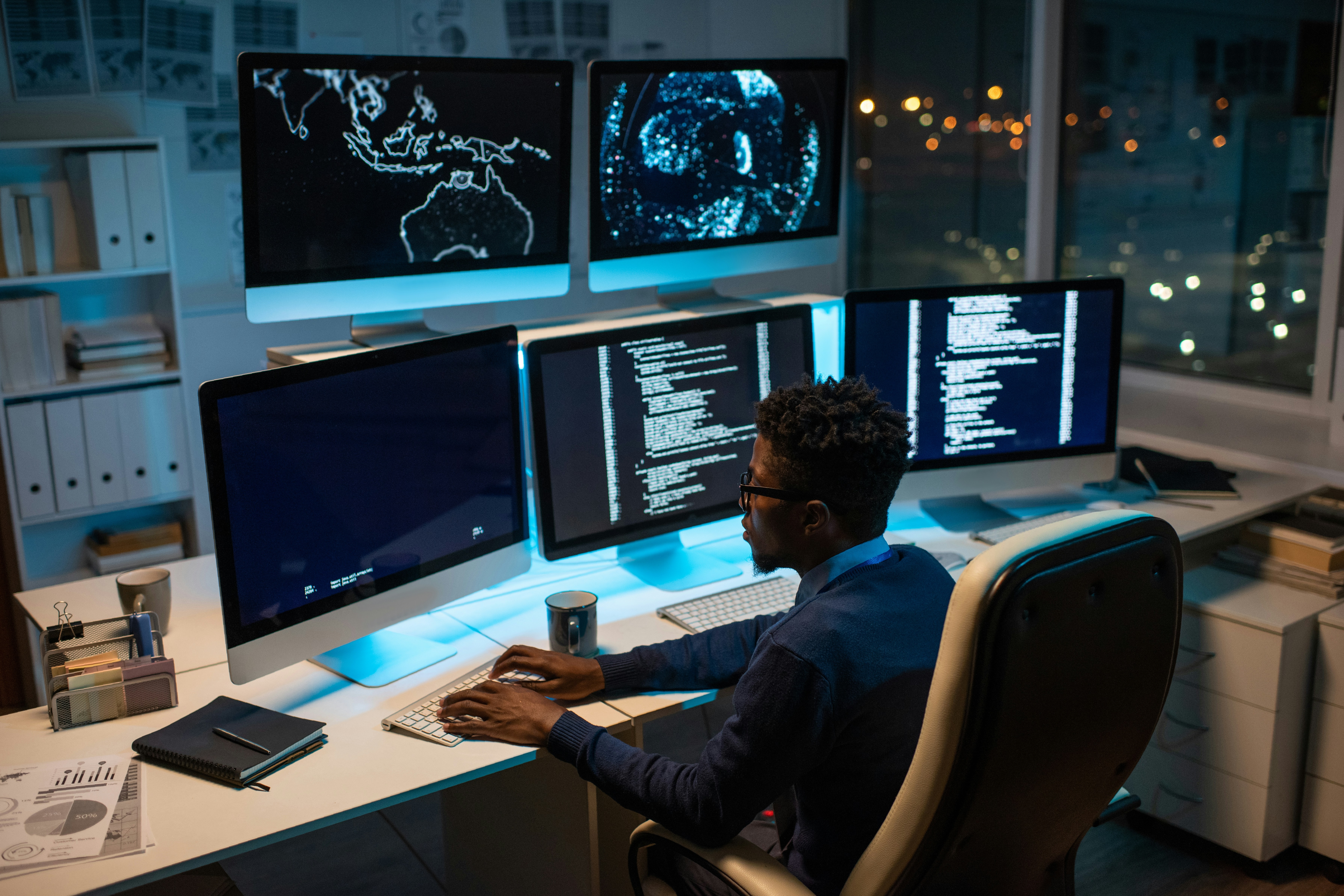 Man monitoring multiple screens with cybersecurity and server data in control room