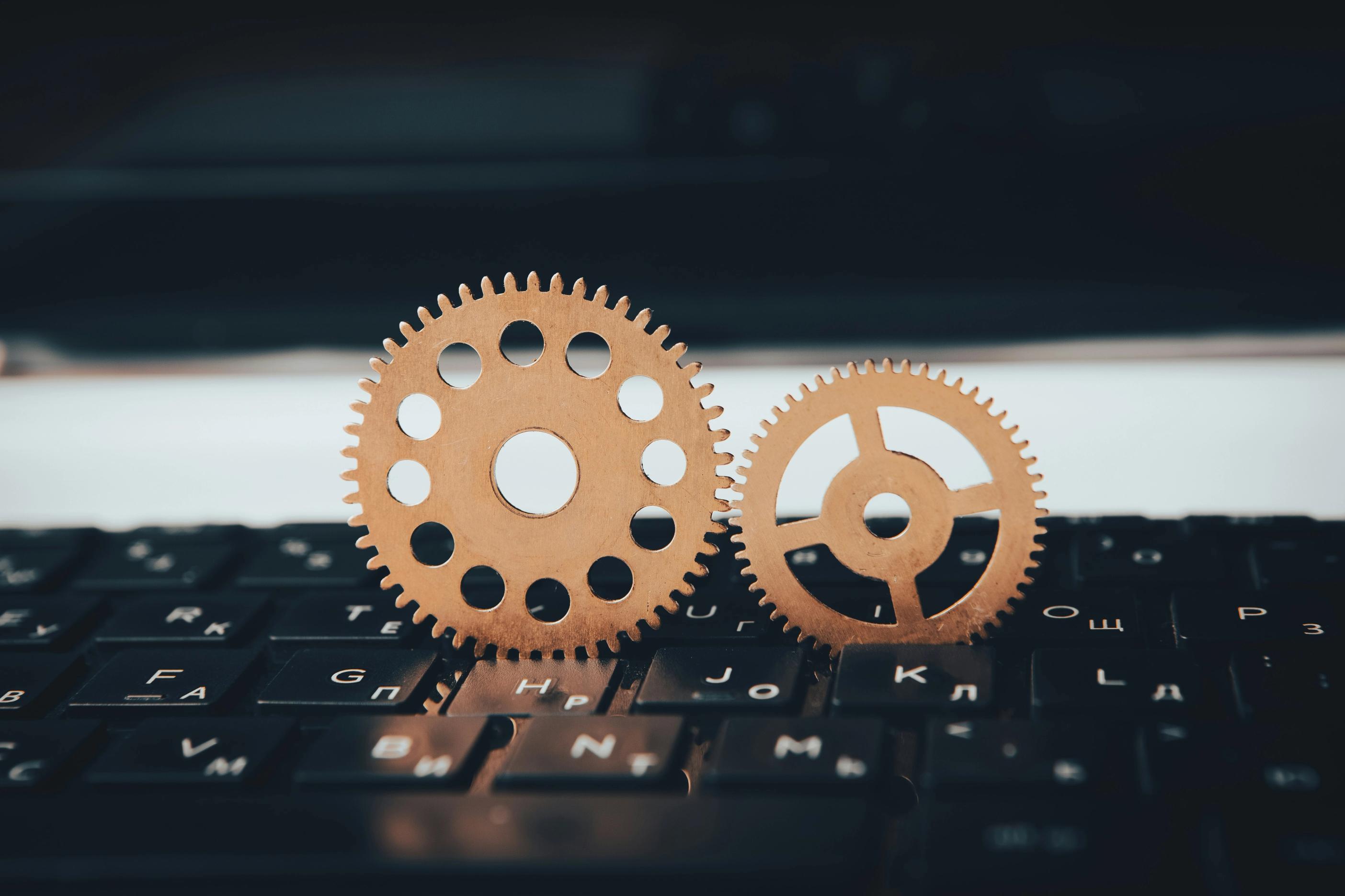 Two interlocking gears placed on a computer keyboard, symbolizing digital automation and system integration.