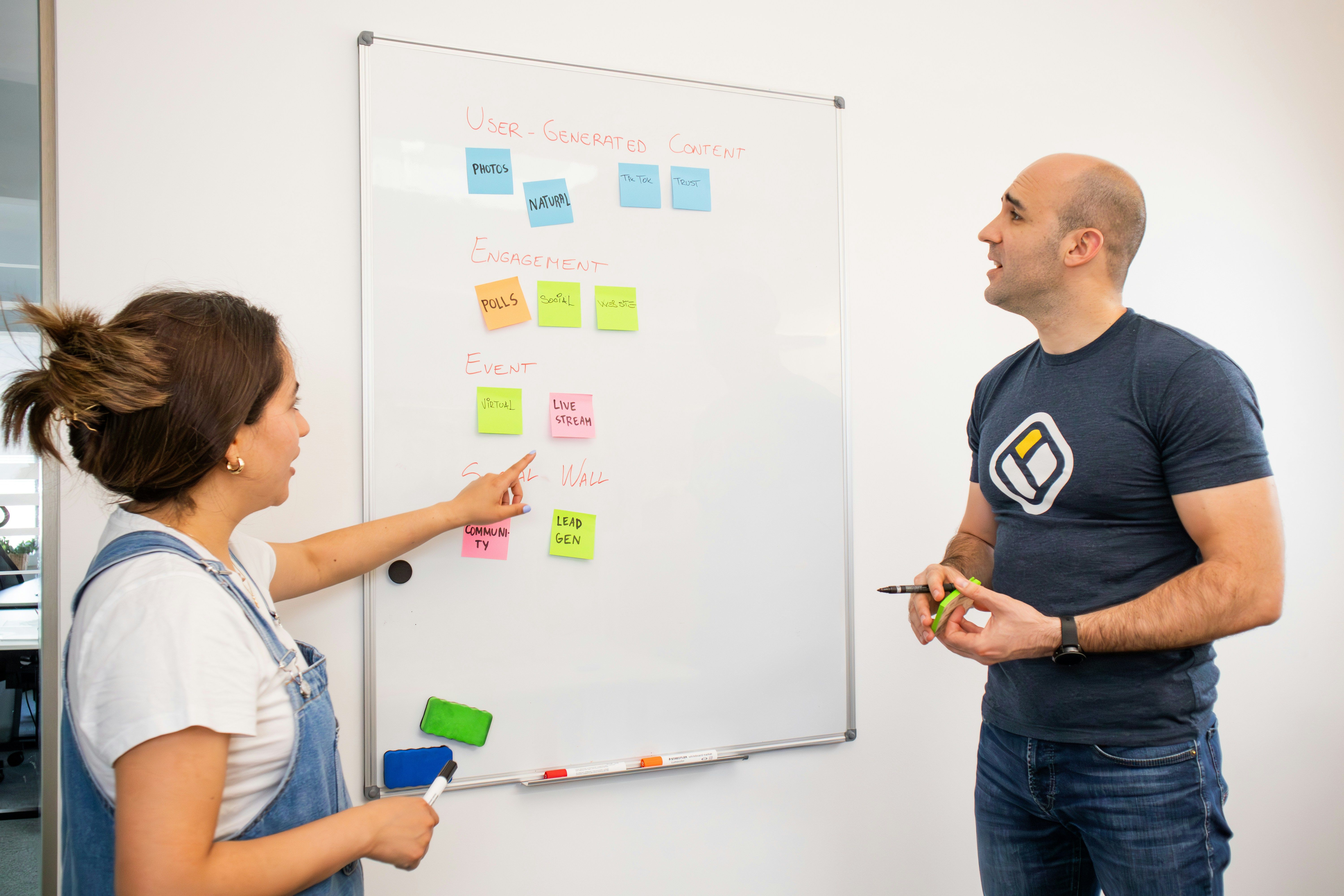 Two team members collaborating at a whiteboard covered with sticky notes during an MVP planning session.