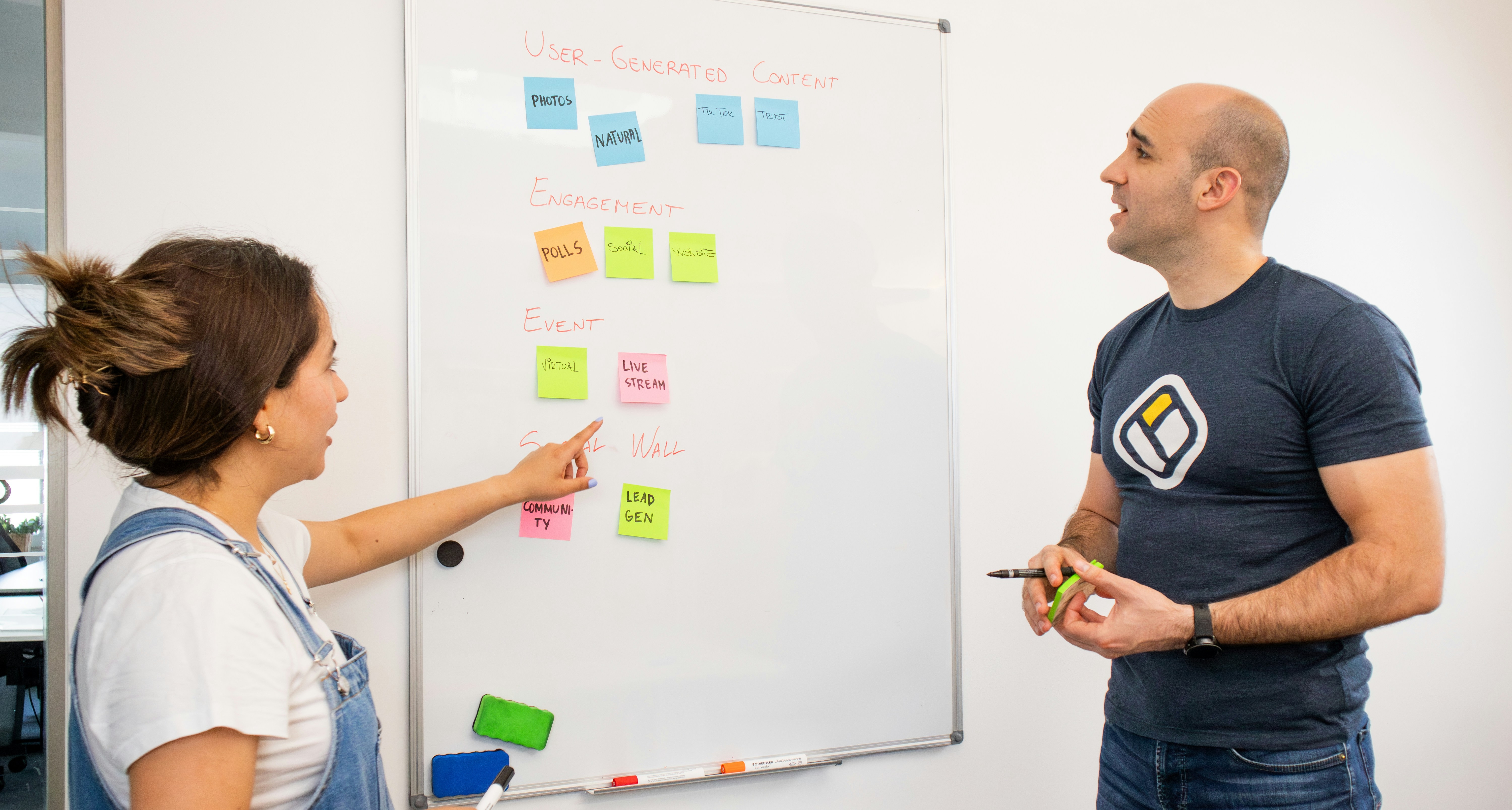 Two team members collaborating at a whiteboard covered with sticky notes during an MVP planning session.