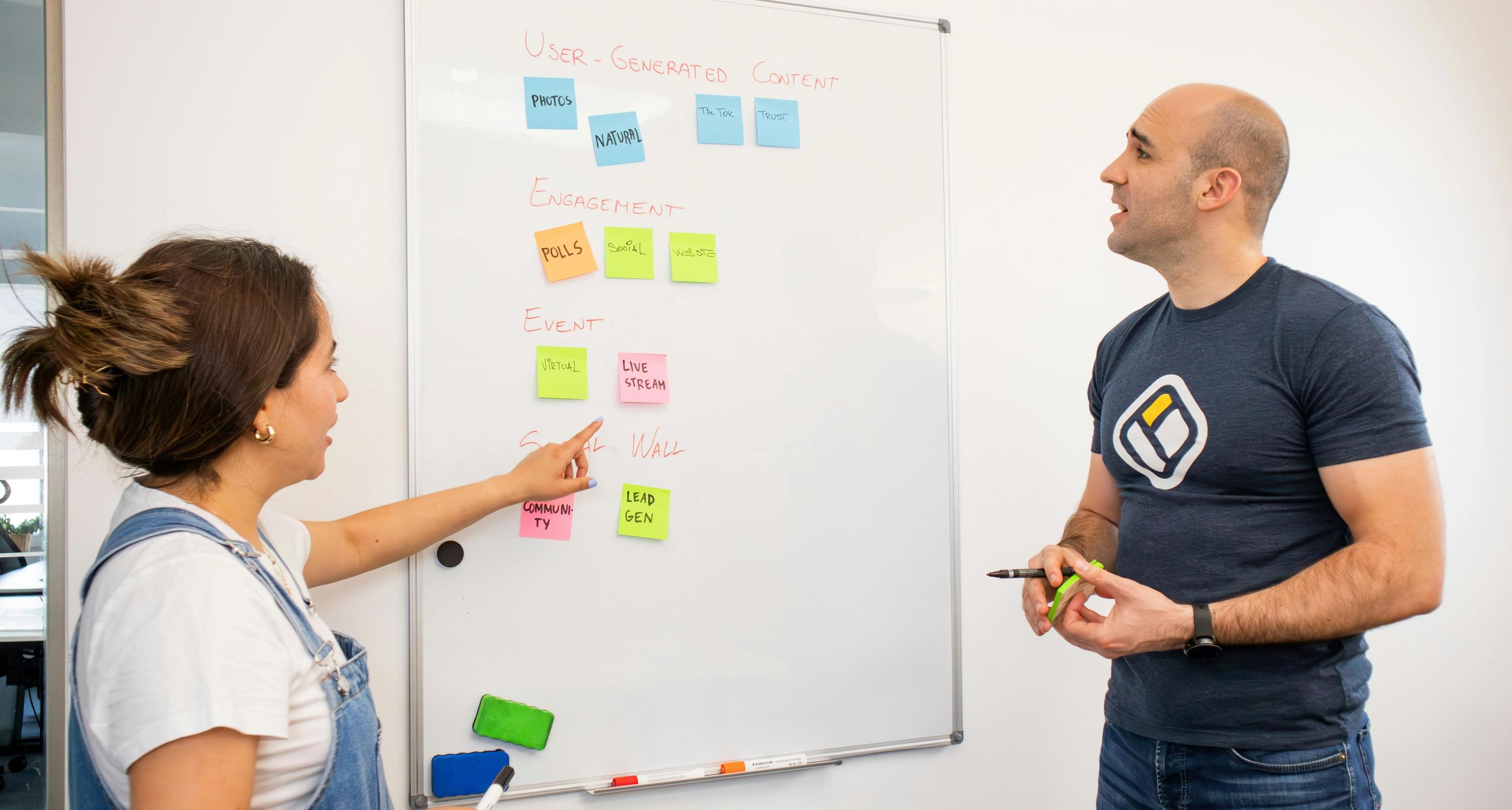 Two team members collaborating at a whiteboard covered with sticky notes during an MVP planning session.