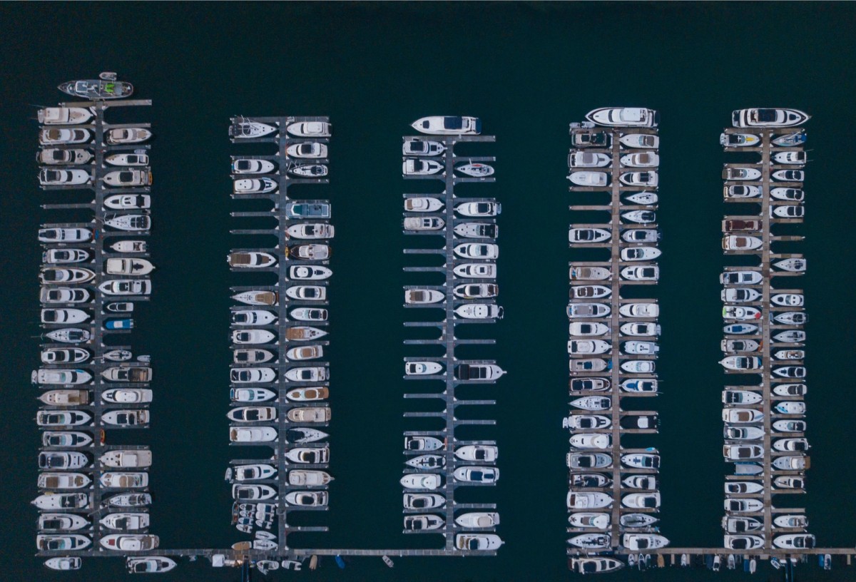 Aerial view of boats docked in organized rows at a marina, symbolizing structure and efficient coordination.