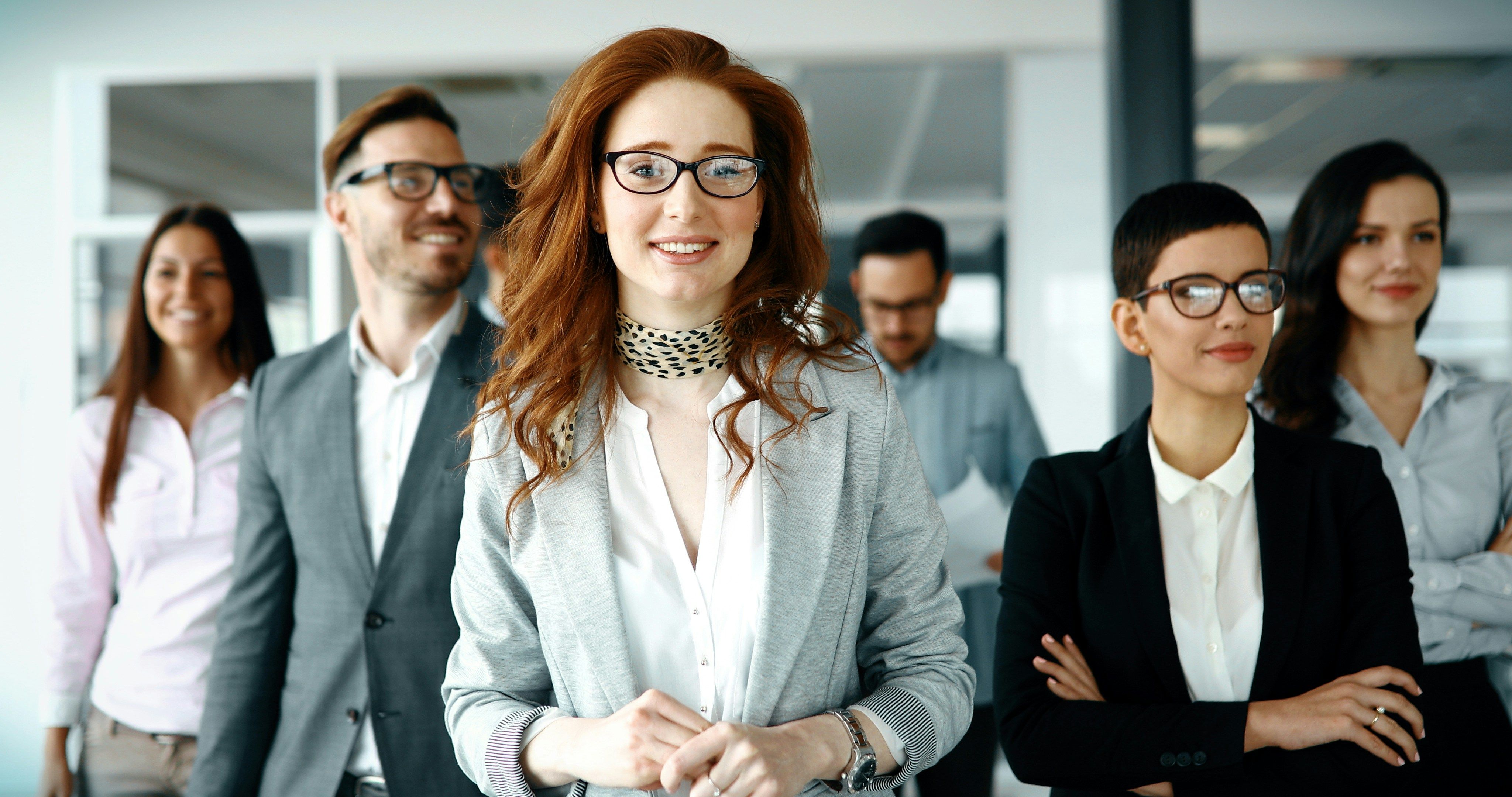 Group of professionals in business attire, confidently standing in an office environment