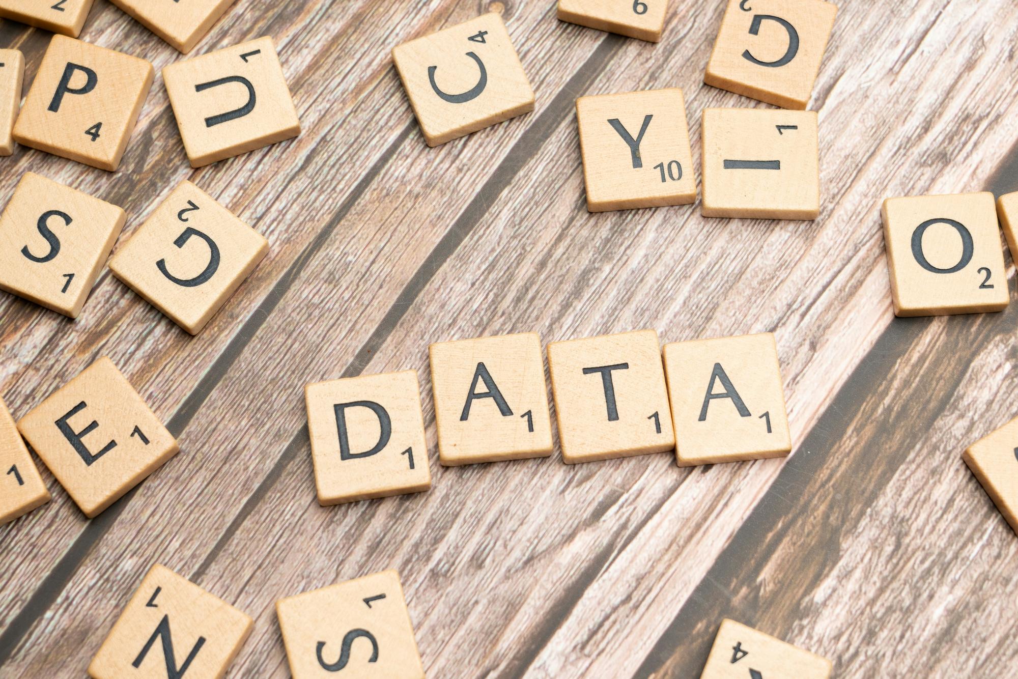 Scrabble letter tiles arranged to spell the word DATA on a wooden surface.