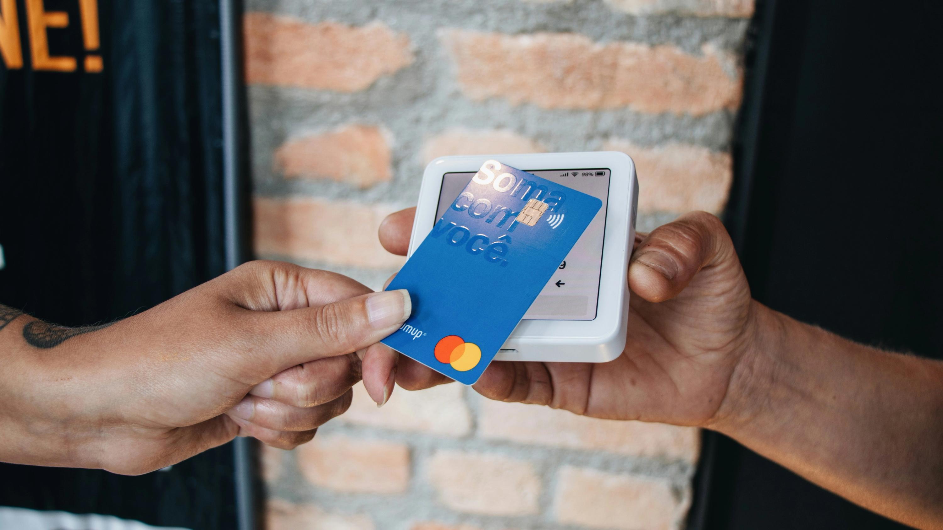 Person tapping Mastercard on a wireless payment terminal for contactless checkout.