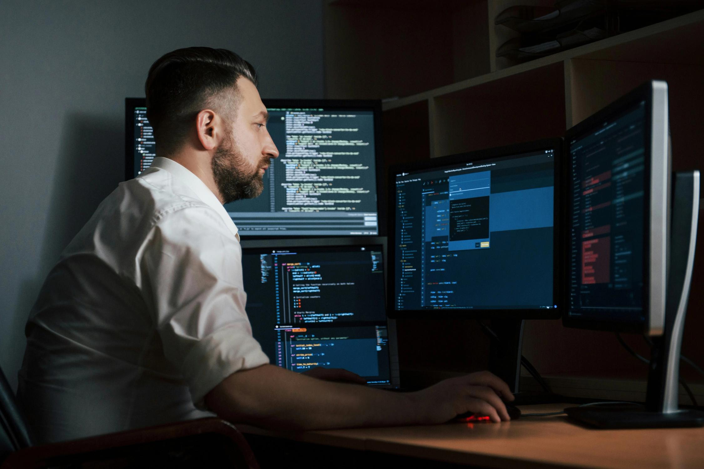 Software developer working on multiple monitors with code displayed, representing custom web development services.