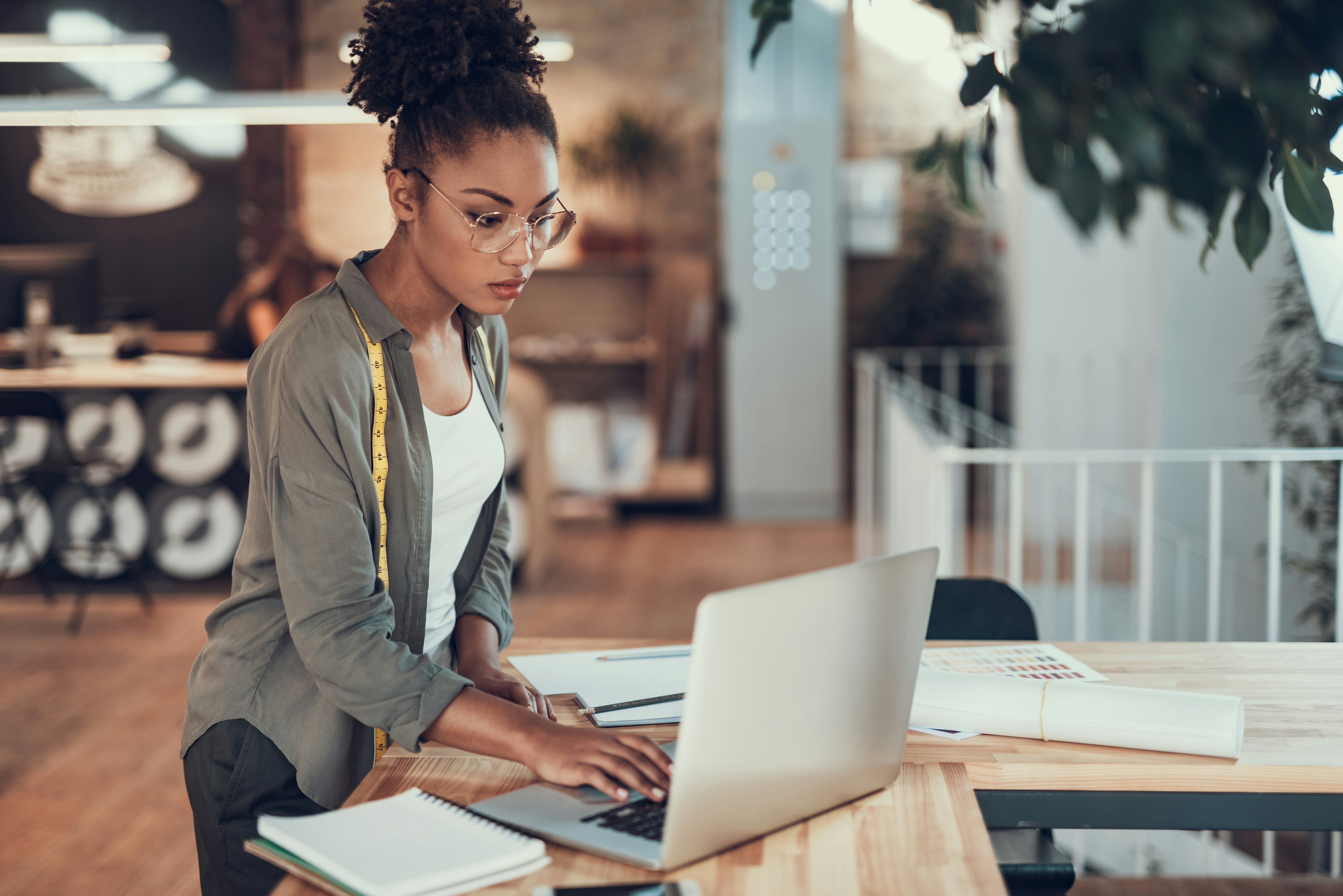 Businesswoman working on a laptop in modern office with design tools on desk