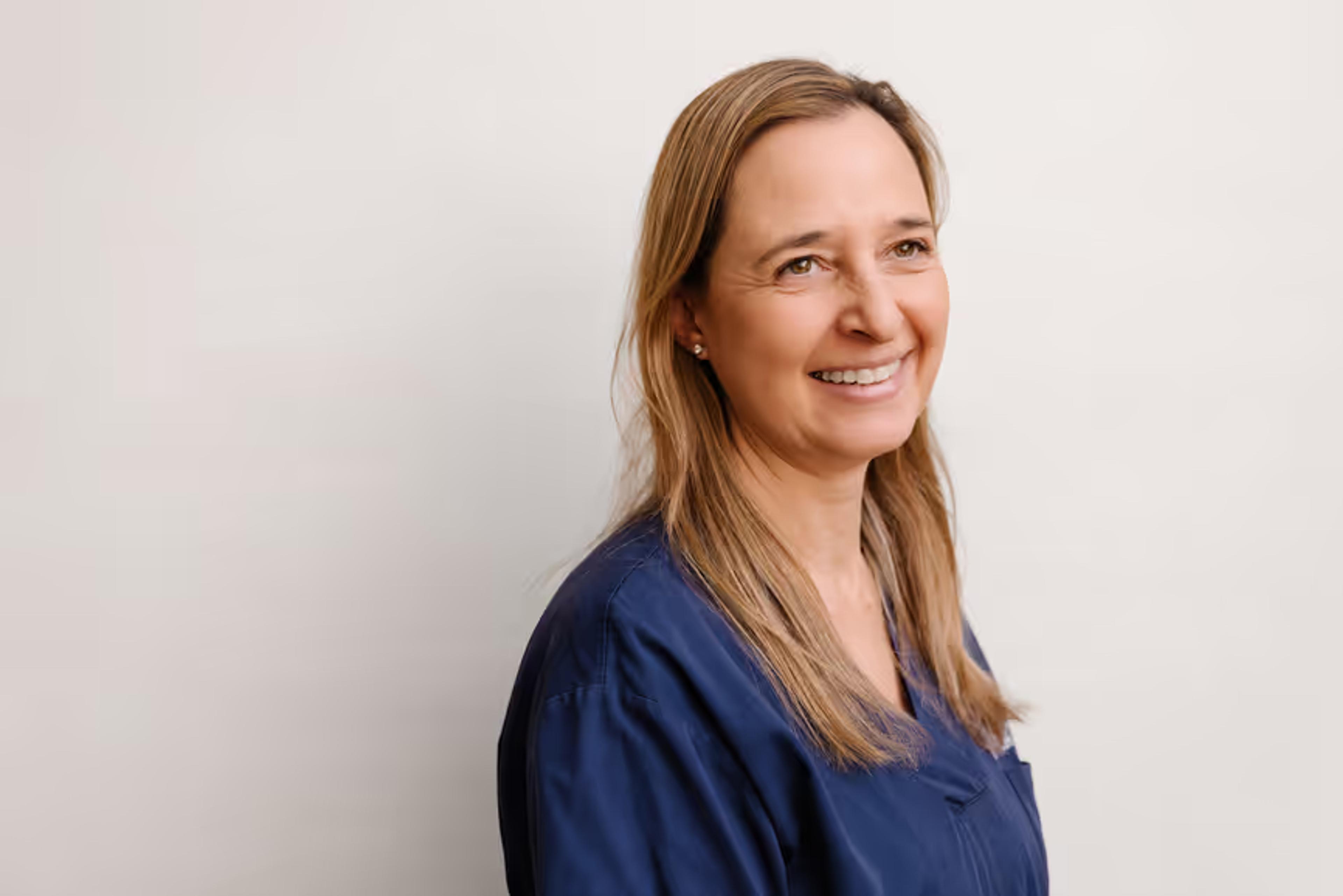 A smiling clinician in navy scrubs