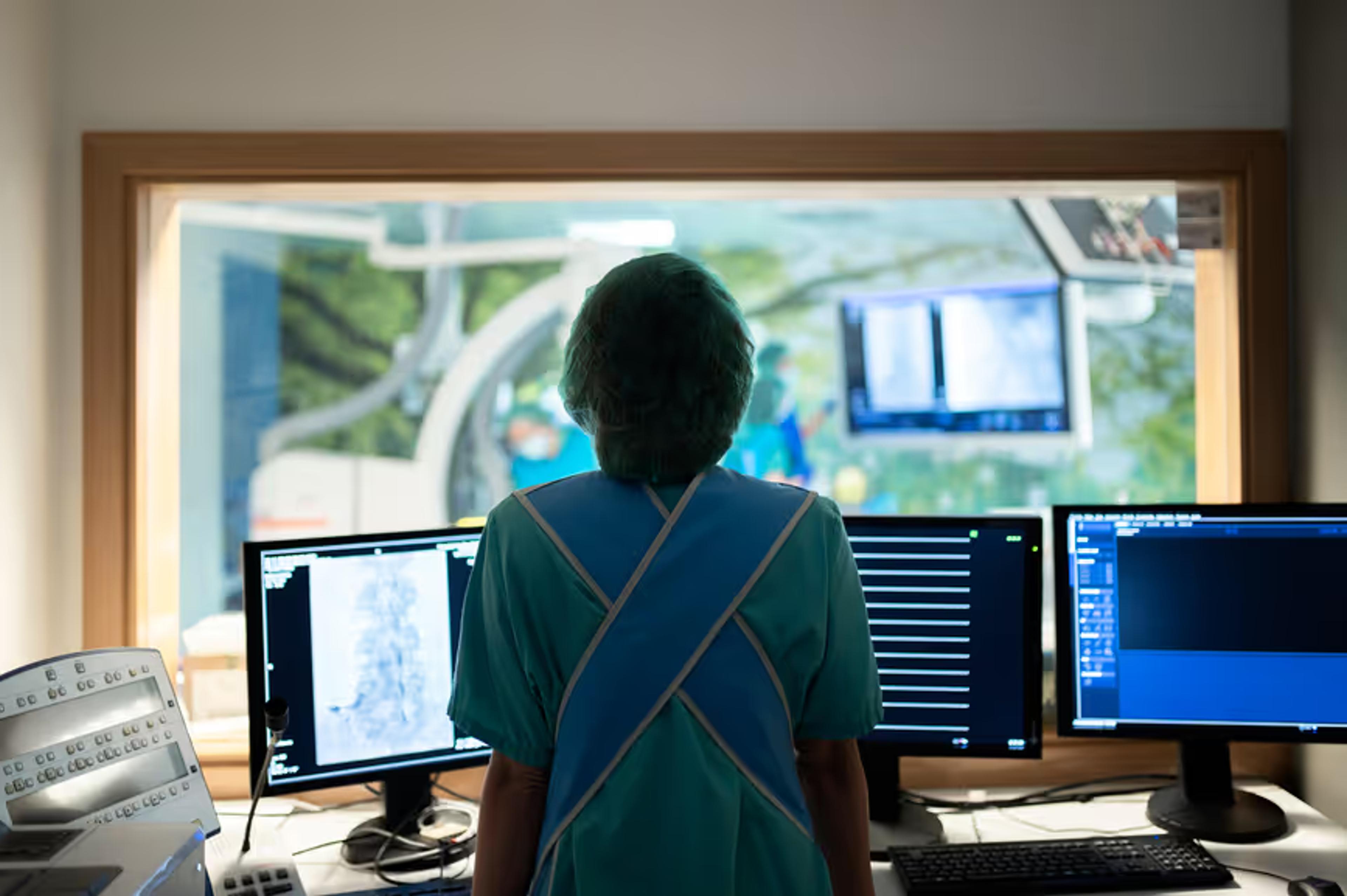 A clinician reviews images on screens in a control room