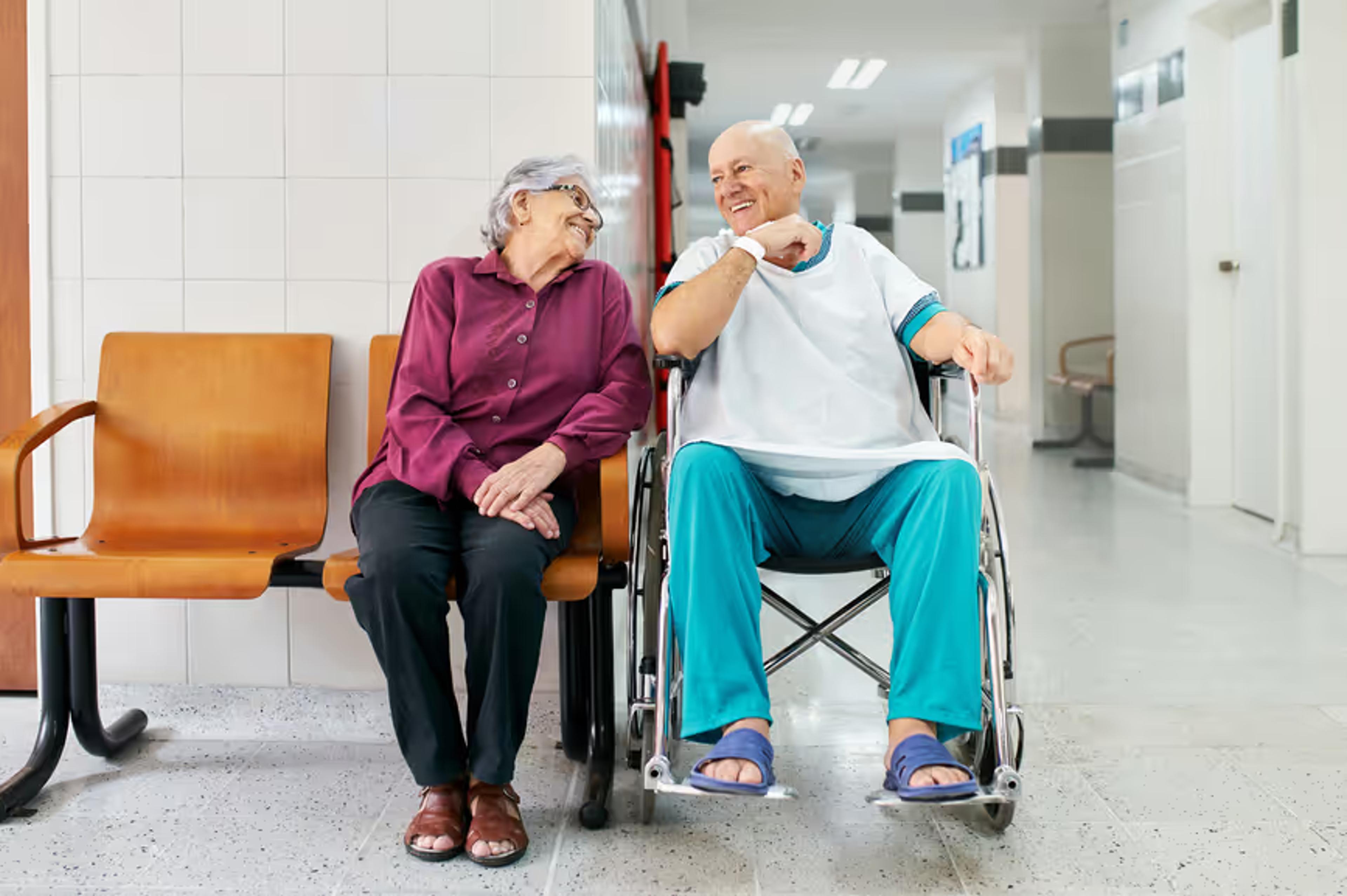 Two older patients chat in a hospital waiting area