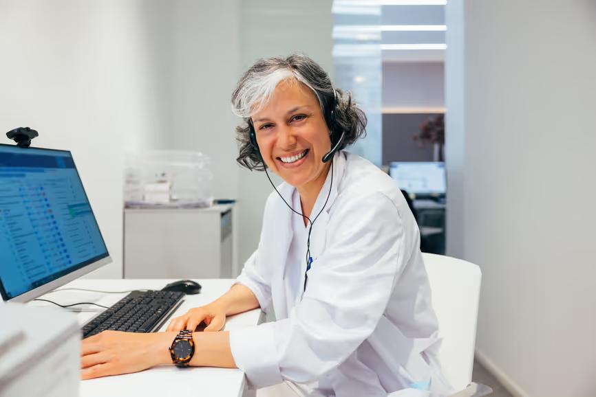 An interpreter wearing a headset smiles at her workstation