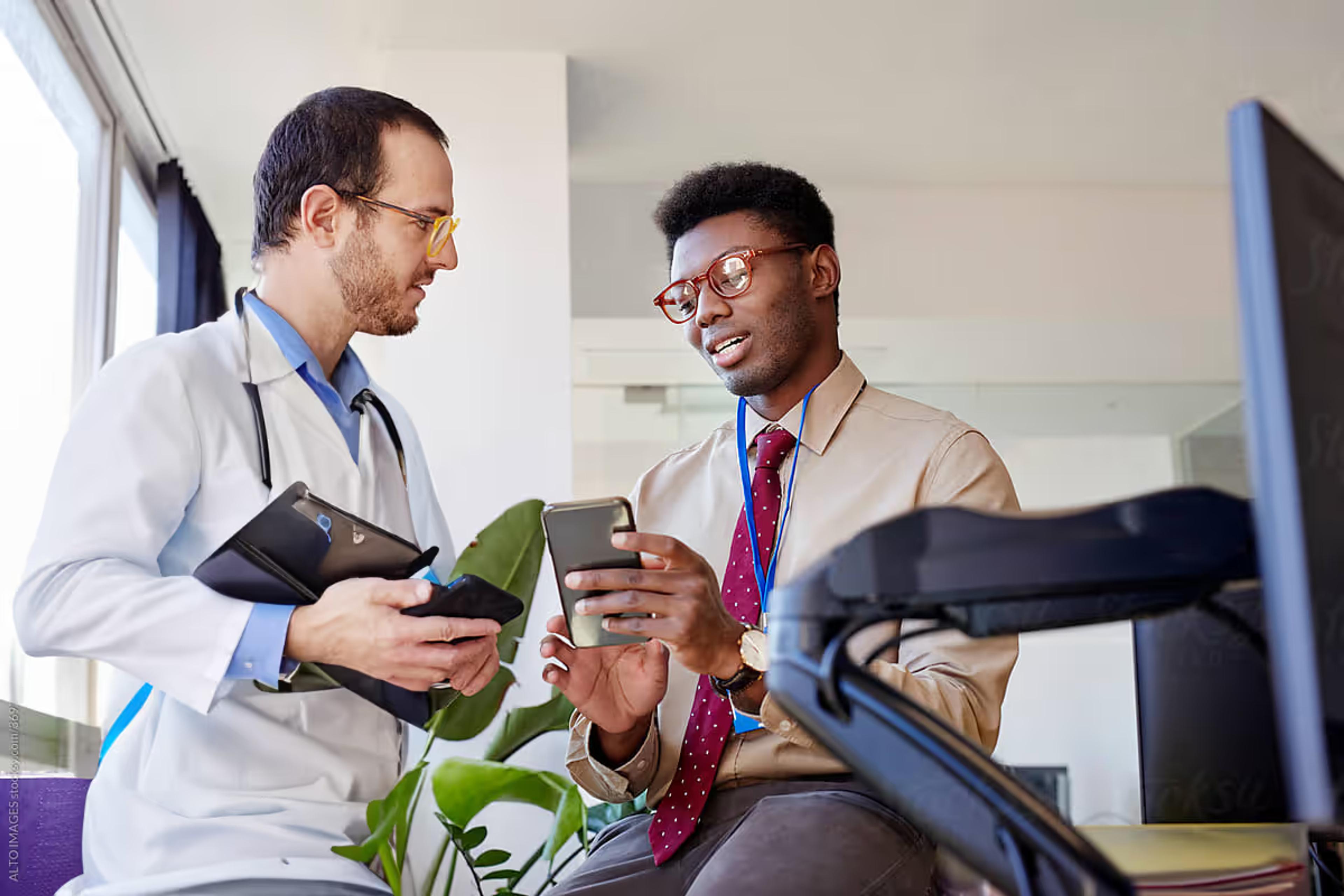 A doctor shows a colleague something on a phone