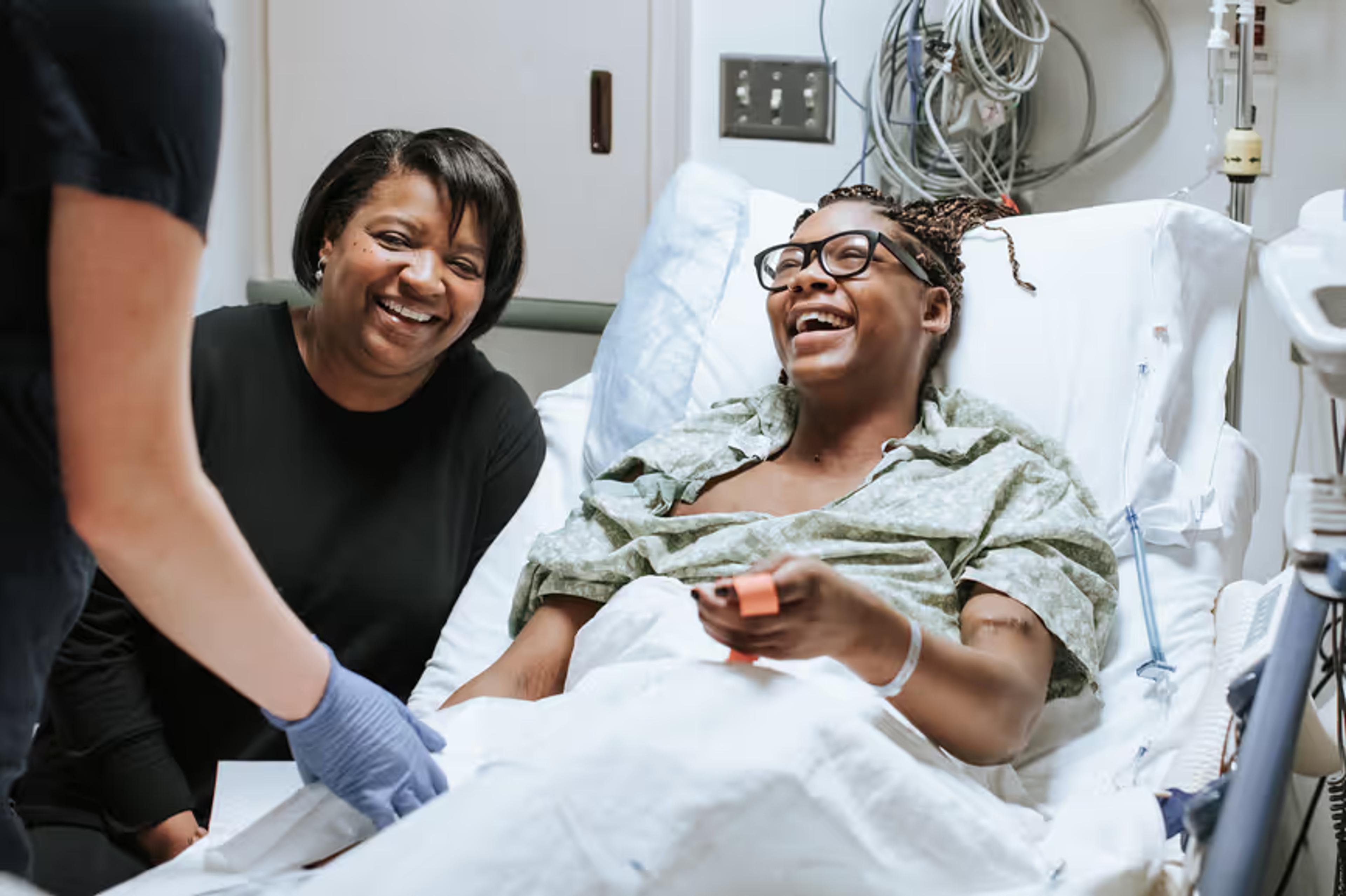 A patient laughs with a nurse at her bedside