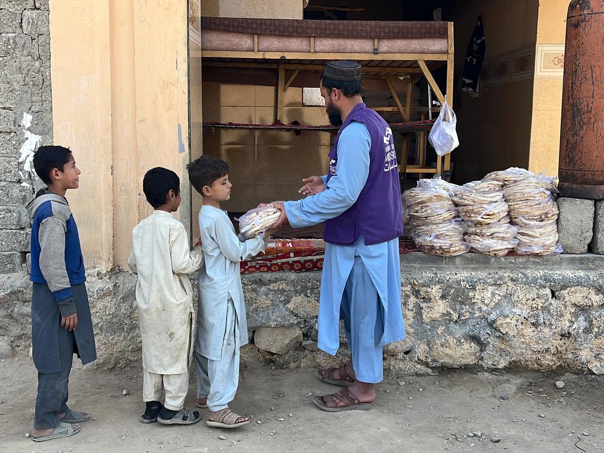 HRM Charity Aid Worker distributing fresh bread to children in Afghanistan next to the Bakery | Human Relief Mission