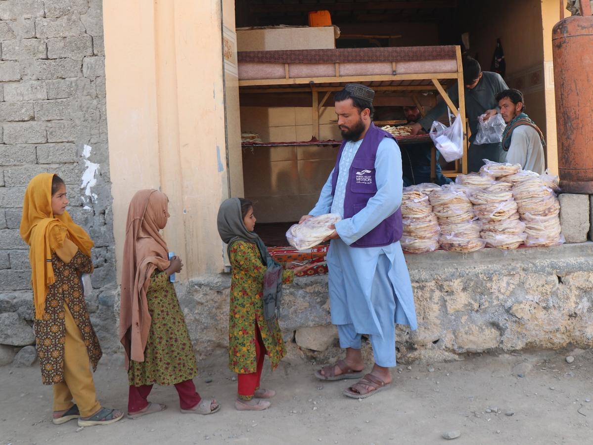 HRM Charity Aid Worker distributing fresh bread to girls outside the Bakery in Afghanistan | Human Relief Mission