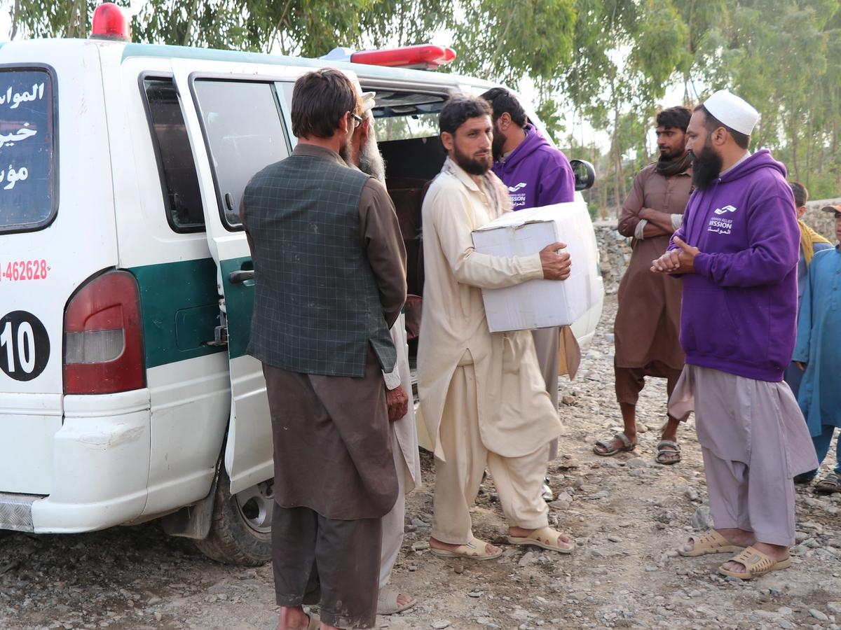 Afghan local receiving aid with next to an ambulance | Human Relief Mission