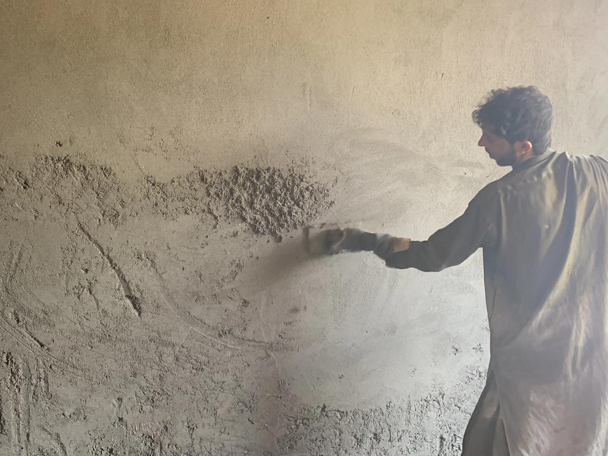 A man putting concrete on the walls of a home in Afghanistan | Human Relief Mission