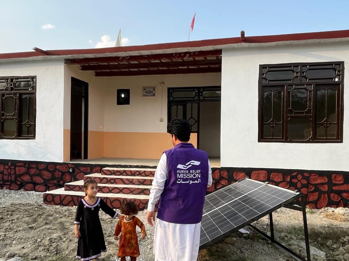 Children in front of a home with HRM aid worker of homes in Afghanistan | Human Relief Mission
