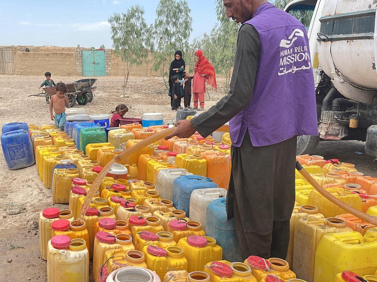 Close up of a man in Afghanistan pouring water into buckets from a Water tanker | Human Relief Mission
