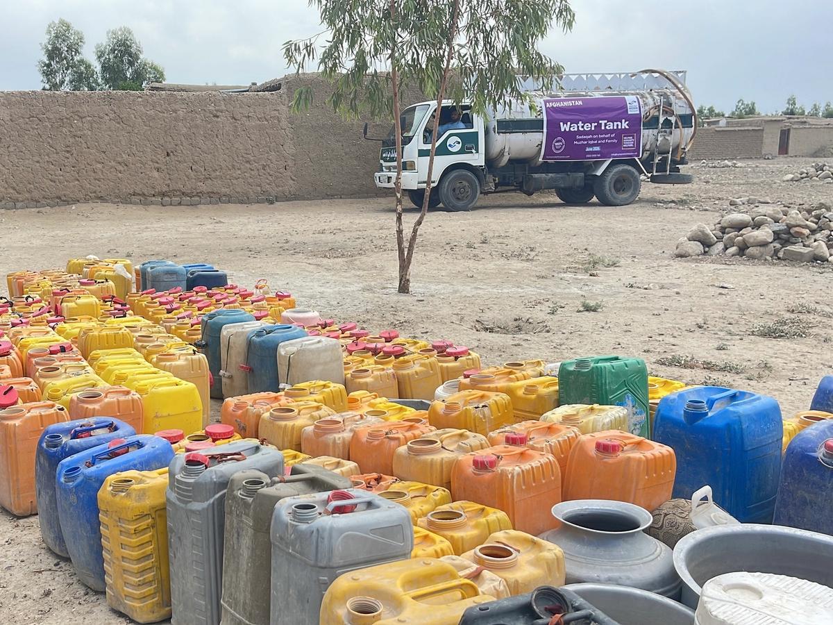 Collection of buckets close up and a Water tanker in the background | Human Relief Mission