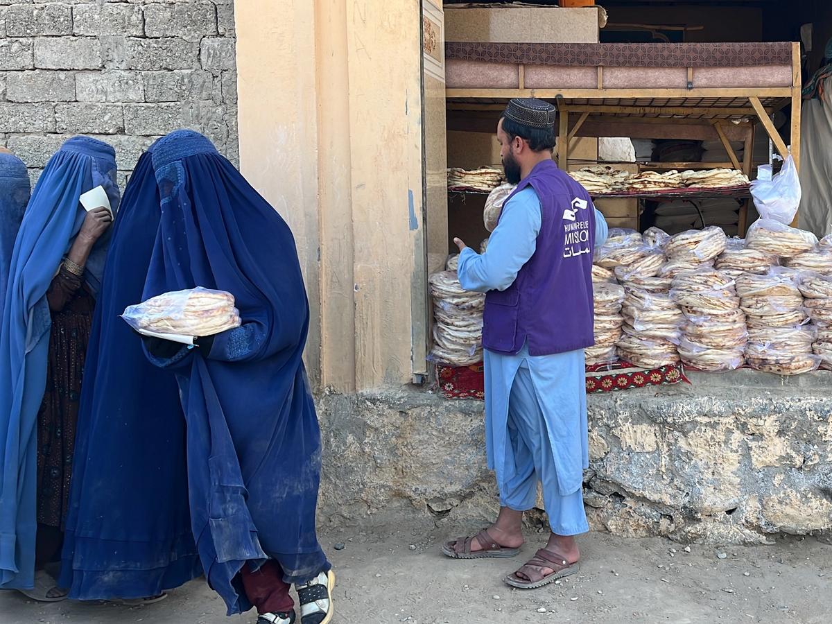 HRM Charity Aid Worker distributing fresh bread to widows in Afghanistan next to the Bakery | Human Relief Mission