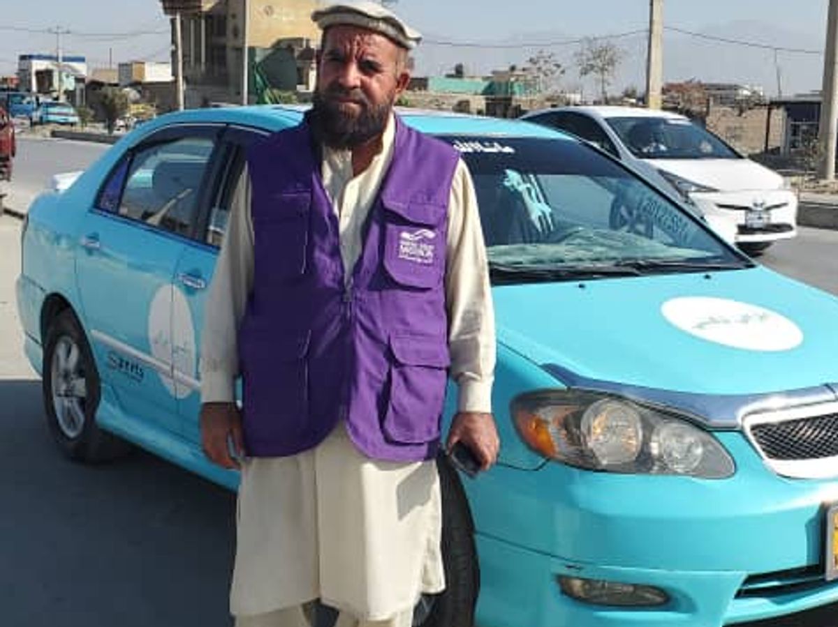 HRM Aid Worker standing next to Taxi
