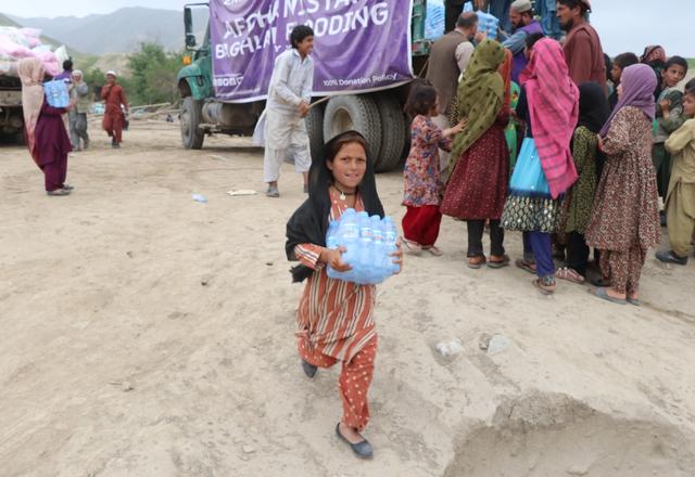 Child carrying a case of water bottles in Afghanistan | Human Relief Mission